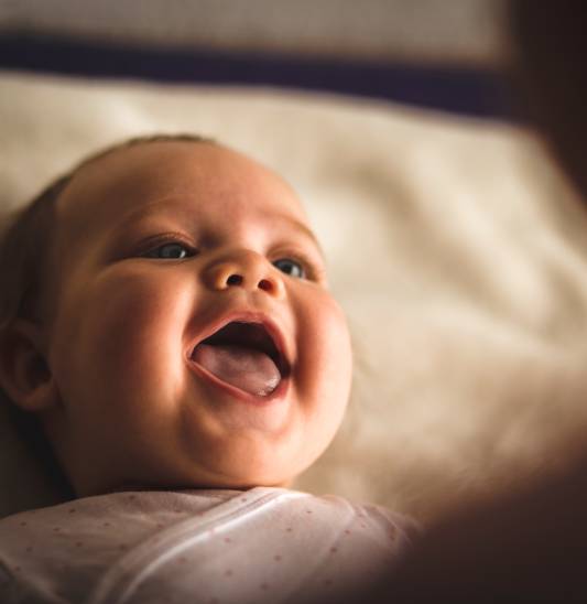 Newborn baby girl laughing and giggling while playing with her mother
